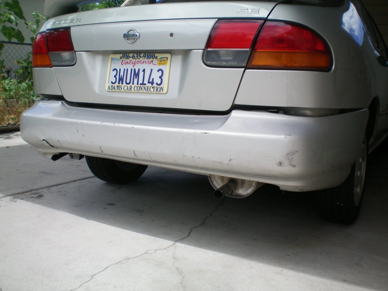Rear of the silver Nissan with California plates, bumper intact before showing the full extent of the accident damage